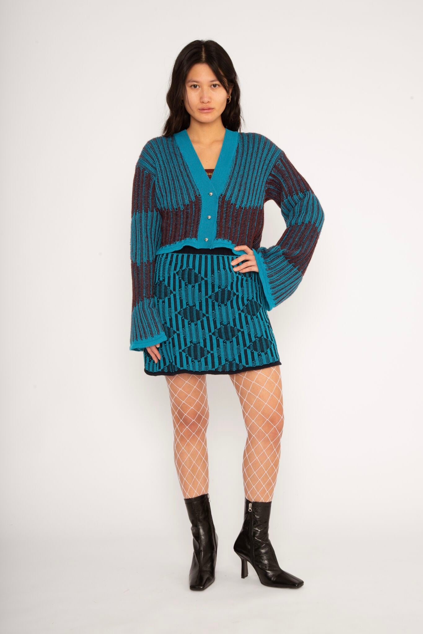 Wavy Wool Cardigan in turquoise and cherry red is a knitted cropped mohair cardigan with flared sleeves and all-over wavy stripes. Detailed with a heart in the back. The cardigan has a ribbed V-shaped neckline, a three-button closure and is cut for a slightly loose fit. The textile is fluffy, non-itchy and comfortable against the skin. The Wavy Wool Cardigan is also available in red and comes in 3 different sizes.