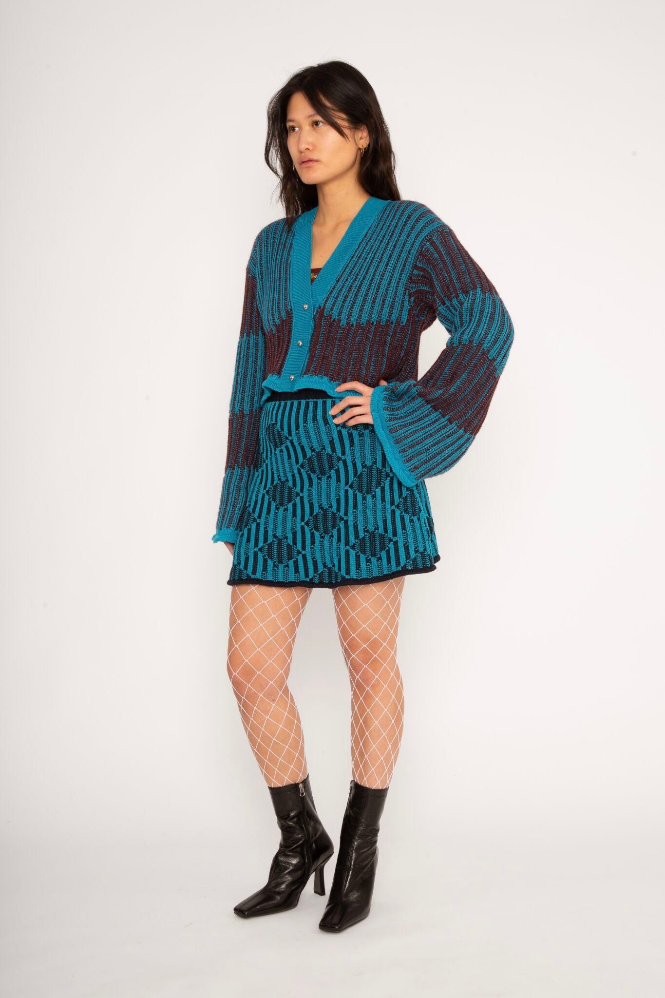 Wavy Wool Cardigan in turquoise and cherry red is a knitted cropped mohair cardigan with flared sleeves and all-over wavy stripes. Detailed with a heart in the back. The cardigan has a ribbed V-shaped neckline, a three-button closure and is cut for a slightly loose fit. The textile is fluffy, non-itchy and comfortable against the skin. The Wavy Wool Cardigan is also available in red and comes in 3 different sizes.