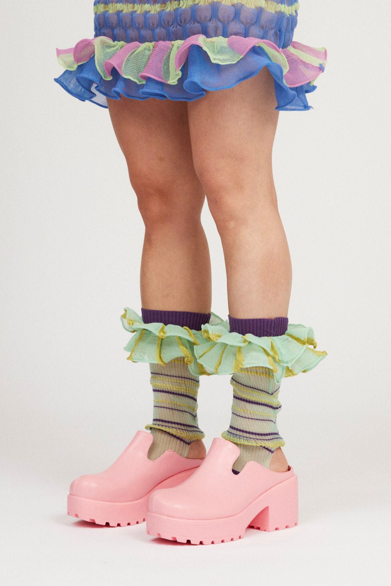 Mini Confetti Frills in mint green and purple are a knitted pair of transparent striped ruffle frills with a ribbed texture. The textile is lightweight, delicate and very flexible. Can be worn on both the arms and legs.