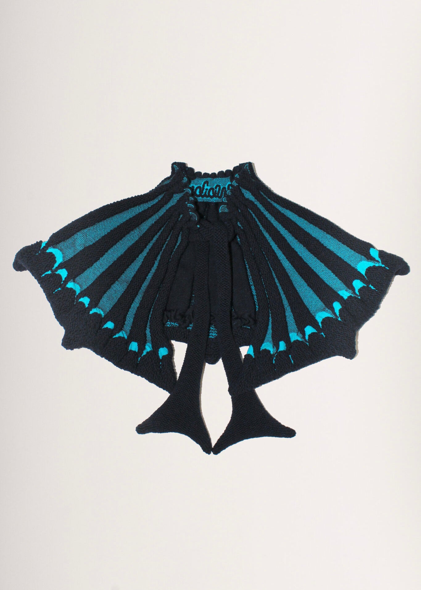 Scallop Collar in navy and turquoise is a 3D jacquard knitted collar in merino wool with scallop edges. This collar is a functional styling pieces, that will keep your neck area warm, while adding some drama to your outfit. The textile is soft, non-itchy and stretchy with a coral like surface. Detailed with ties to adjust the fit with. Also available in khaki.