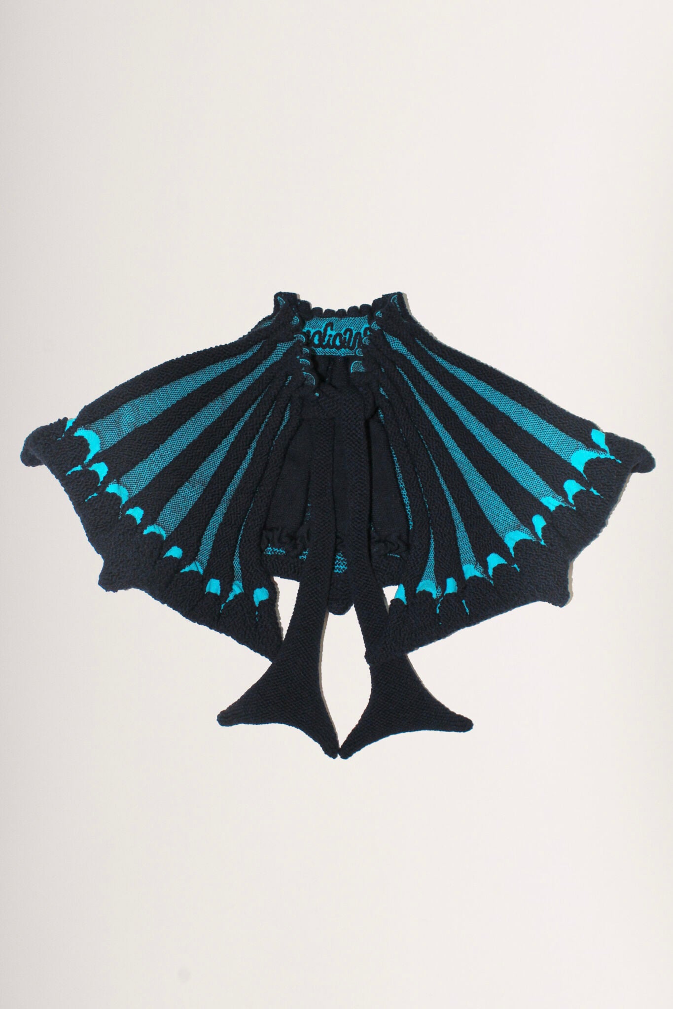 Scallop Collar in navy and turquoise is a 3D jacquard knitted collar in merino wool with scallop edges. This collar is a functional styling pieces, that will keep your neck area warm, while adding some drama to your outfit. The textile is soft, non-itchy and stretchy with a coral like surface. Detailed with ties to adjust the fit with. Also available in khaki.