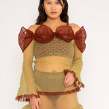 Bubble Bell Top in khaki and cherry red is a transparent knitted off-shoulder top in a ribbed bubble texture with ruffles and bell sleeves. The top has a close fit body with long sleeves and a voluminous adjustable neckline detailed with a melange rim with a logo in the back. The textile is lightweight, delicate and very flexible, meaning the dress adapts to body wearing it. The Bubble Bell Top is also available in teal and comes in 2 different sizes.