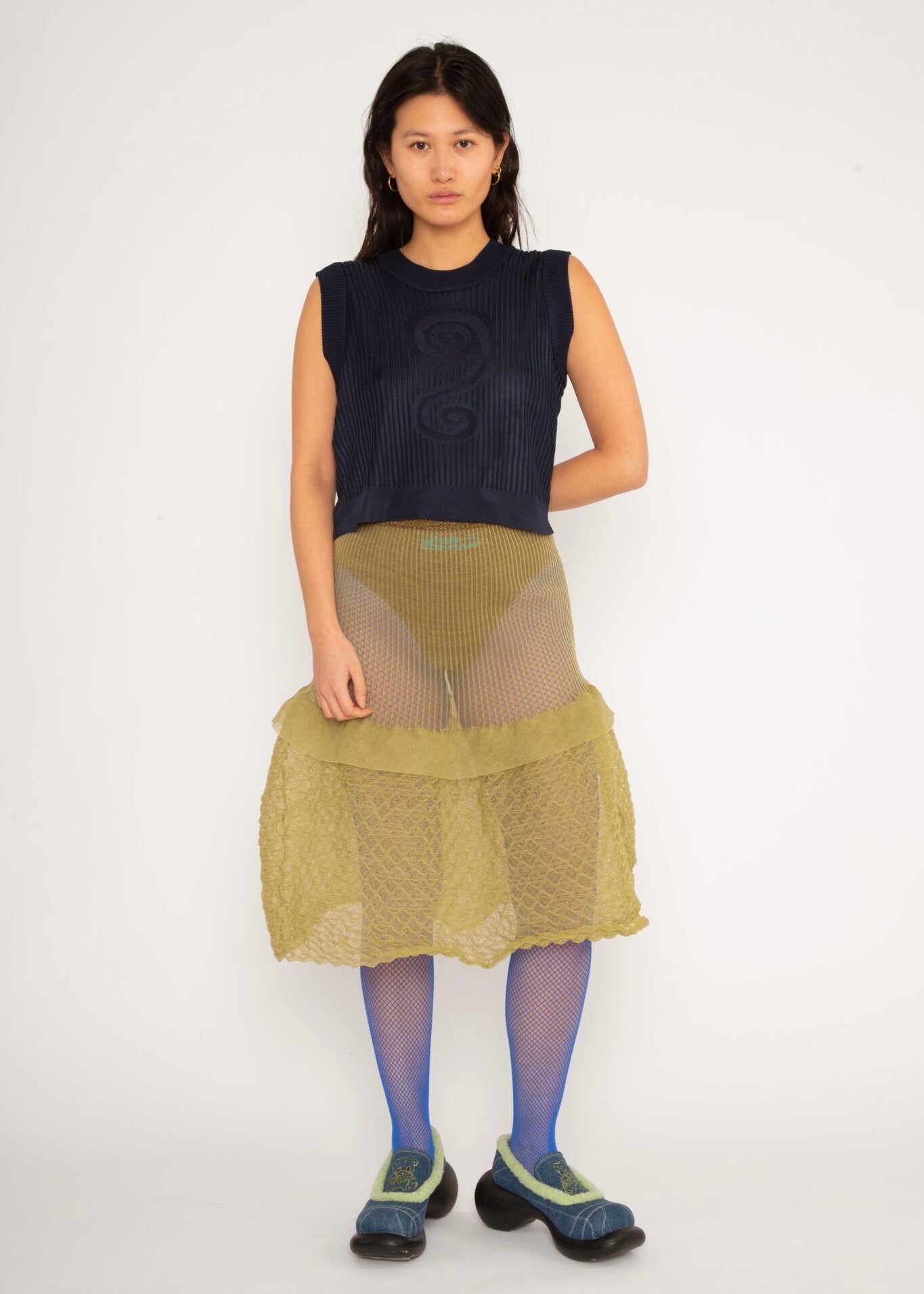 Spiral Top in navy is a knitted cropped crew neck top with spiral artwork. The textile has a shine to it and is lightweight with a smooth and soft feel against the body. The top has a slightly loose fit and is detailed with ribbed rims. The Spiral Top is available in 3 different sizes.