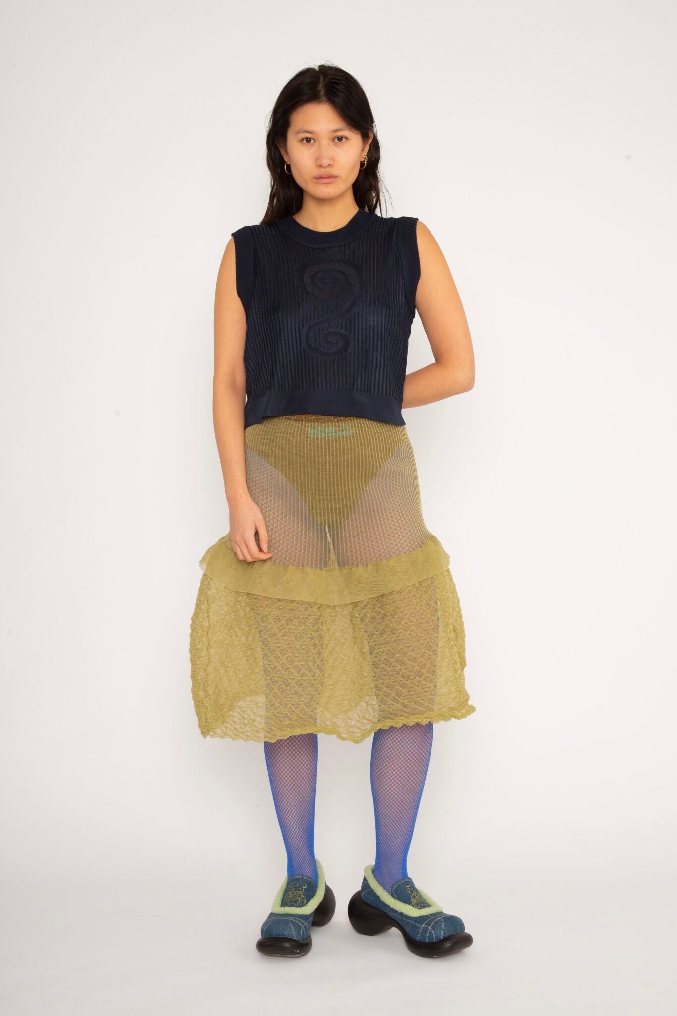Spiral Top in navy is a knitted cropped crew neck top with spiral artwork. The textile has a shine to it and is lightweight with a smooth and soft feel against the body. The top has a slightly loose fit and is detailed with ribbed rims. The Spiral Top is available in 3 different sizes.