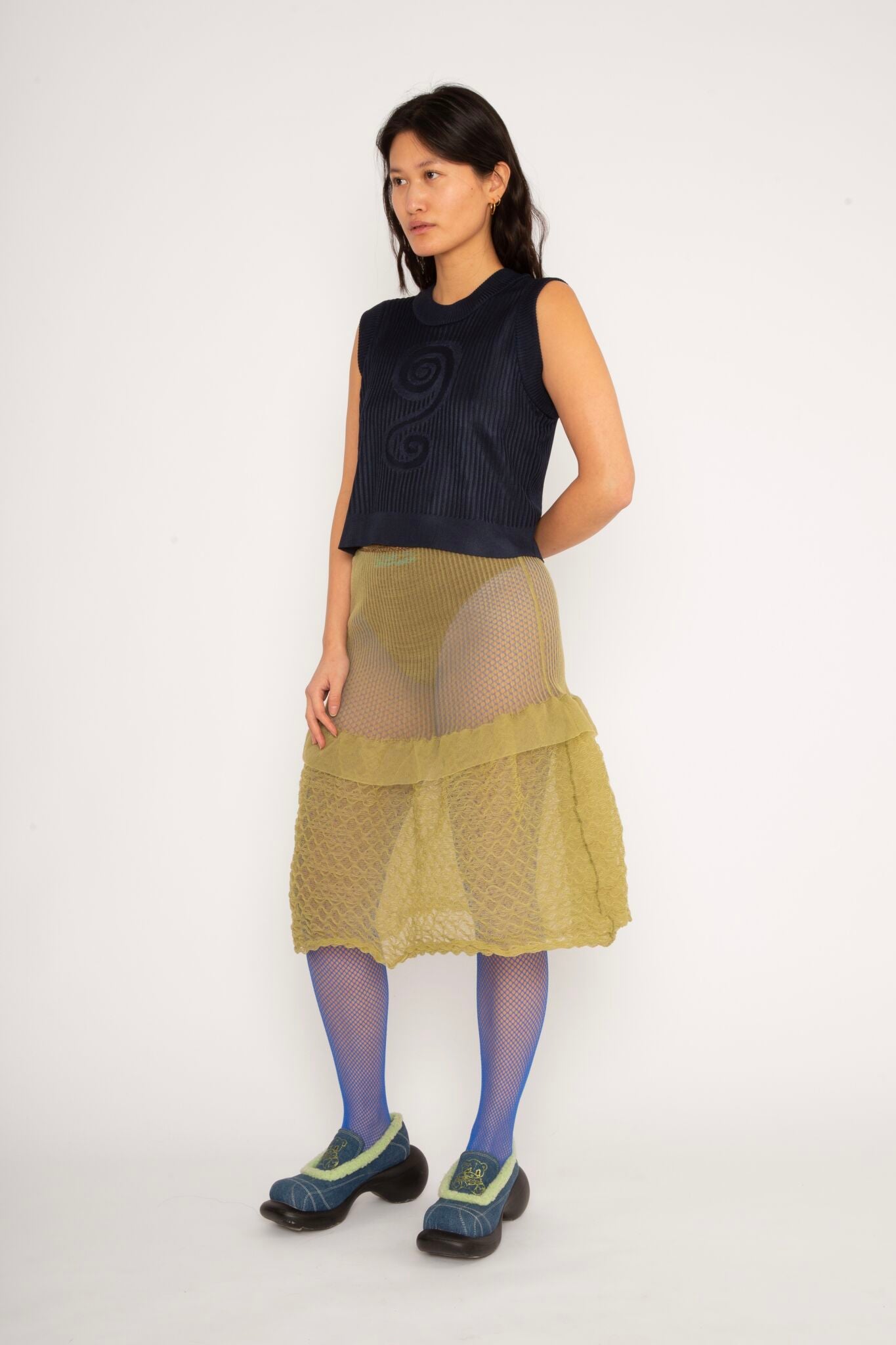 Spiral Top in navy is a knitted cropped crew neck top with spiral artwork. The textile has a shine to it and is lightweight with a smooth and soft feel against the body. The top has a slightly loose fit and is detailed with ribbed rims. The Spiral Top is available in 3 different sizes.