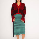 Wavy Wool Cardigan in red and black is a knitted cropped mohair cardigan with flared sleeves and all-over wavy stripes. Detailed with a heart in the back. The cardigan has a ribbed V-shaped neckline, a three-button closure and is cut for a slightly loose fit. The textile is fluffy, non-itchy and comfortable against the skin. The Wavy Wool Cardigan is also available in turquoise and comes in 3 different sizes.