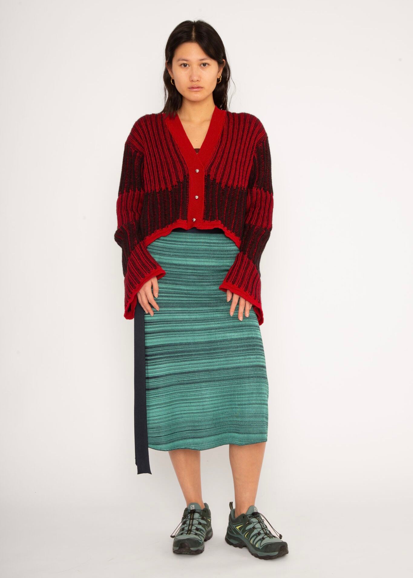 Wavy Wool Cardigan in red and black is a knitted cropped mohair cardigan with flared sleeves and all-over wavy stripes. Detailed with a heart in the back. The cardigan has a ribbed V-shaped neckline, a three-button closure and is cut for a slightly loose fit. The textile is fluffy, non-itchy and comfortable against the skin. The Wavy Wool Cardigan is also available in turquoise and comes in 3 different sizes.