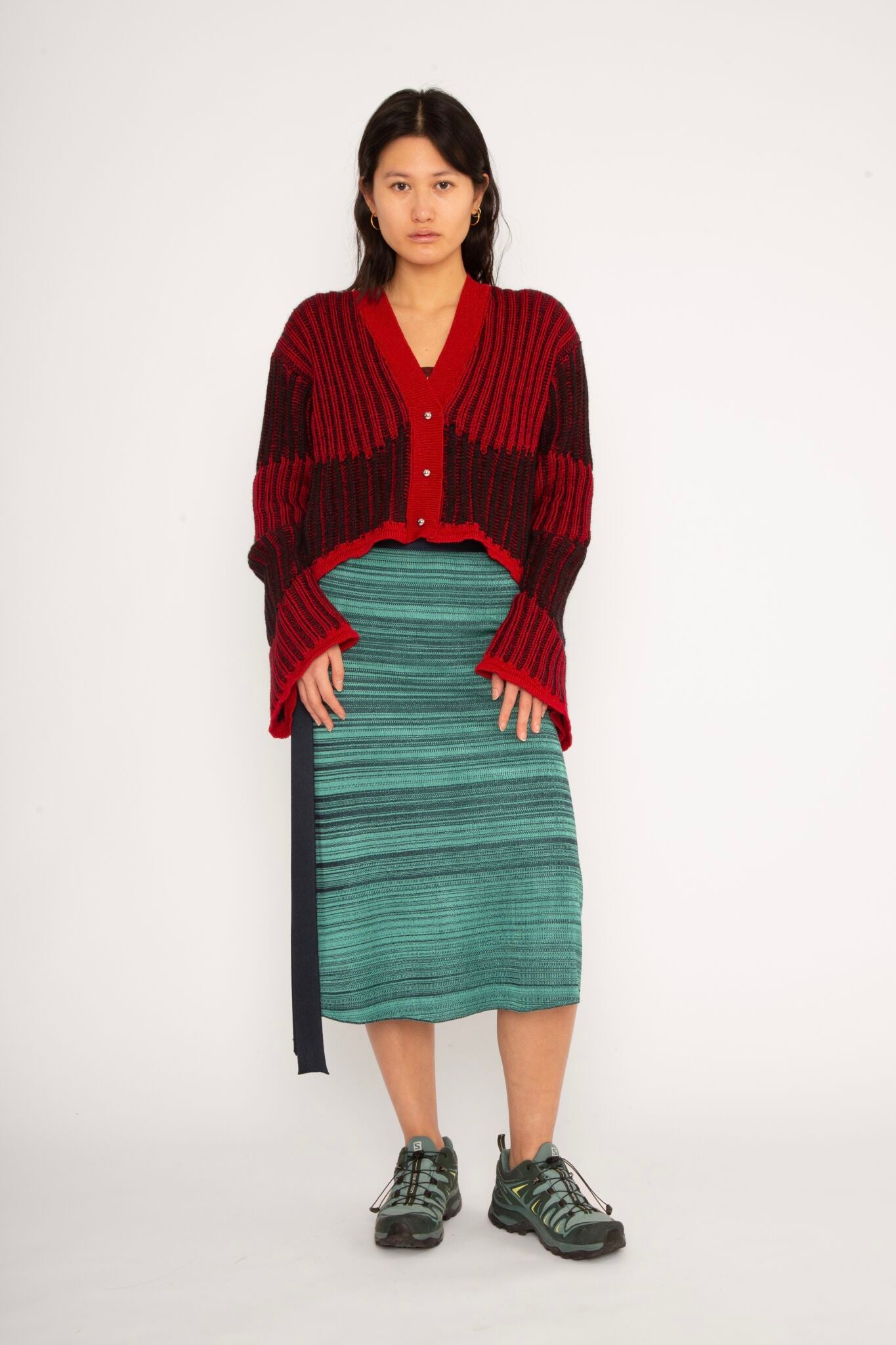 Wavy Wool Cardigan in red and black is a knitted cropped mohair cardigan with flared sleeves and all-over wavy stripes. Detailed with a heart in the back. The cardigan has a ribbed V-shaped neckline, a three-button closure and is cut for a slightly loose fit. The textile is fluffy, non-itchy and comfortable against the skin. The Wavy Wool Cardigan is also available in turquoise and comes in 3 different sizes.