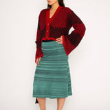 Wavy Wool Cardigan in red and black is a knitted cropped mohair cardigan with flared sleeves and all-over wavy stripes. Detailed with a heart in the back. The cardigan has a ribbed V-shaped neckline, a three-button closure and is cut for a slightly loose fit. The textile is fluffy, non-itchy and comfortable against the skin. The Wavy Wool Cardigan is also available in turquoise and comes in 3 different sizes.