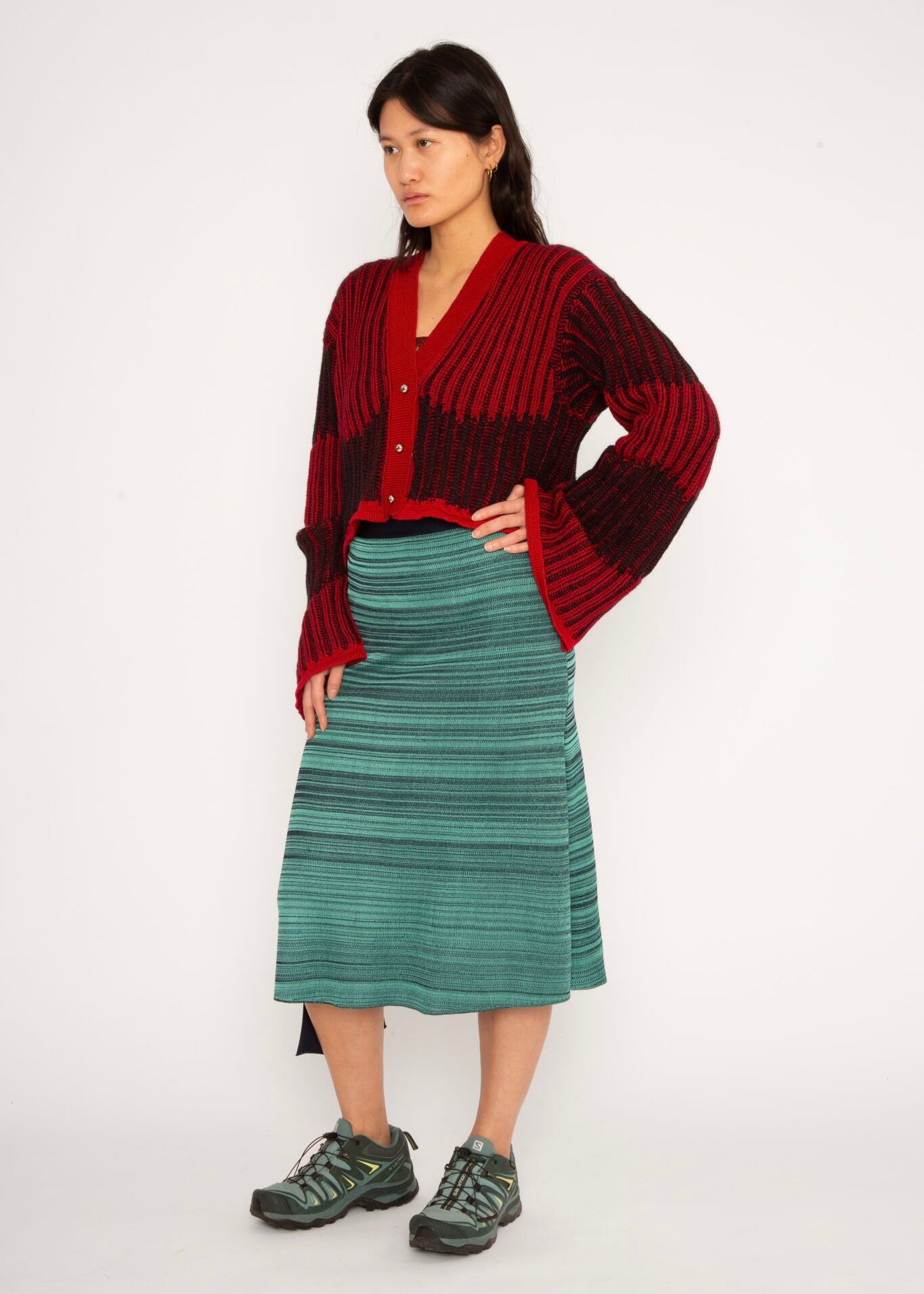 Wavy Wool Cardigan in red and black is a knitted cropped mohair cardigan with flared sleeves and all-over wavy stripes. Detailed with a heart in the back. The cardigan has a ribbed V-shaped neckline, a three-button closure and is cut for a slightly loose fit. The textile is fluffy, non-itchy and comfortable against the skin. The Wavy Wool Cardigan is also available in turquoise and comes in 3 different sizes.