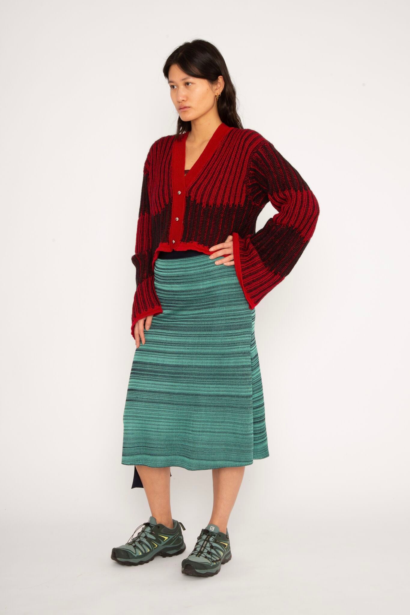 Wavy Wool Cardigan in red and black is a knitted cropped mohair cardigan with flared sleeves and all-over wavy stripes. Detailed with a heart in the back. The cardigan has a ribbed V-shaped neckline, a three-button closure and is cut for a slightly loose fit. The textile is fluffy, non-itchy and comfortable against the skin. The Wavy Wool Cardigan is also available in turquoise and comes in 3 different sizes.