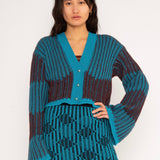 Wavy Wool Cardigan in turquoise and cherry red is a knitted cropped mohair cardigan with flared sleeves and all-over wavy stripes. Detailed with a heart in the back. The cardigan has a ribbed V-shaped neckline, a three-button closure and is cut for a slightly loose fit. The textile is fluffy, non-itchy and comfortable against the skin. The Wavy Wool Cardigan is also available in red and comes in 3 different sizes.