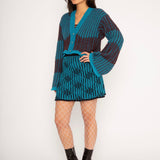 Wavy Wool Cardigan in turquoise and cherry red is a knitted cropped mohair cardigan with flared sleeves and all-over wavy stripes. Detailed with a heart in the back. The cardigan has a ribbed V-shaped neckline, a three-button closure and is cut for a slightly loose fit. The textile is fluffy, non-itchy and comfortable against the skin. The Wavy Wool Cardigan is also available in red and comes in 3 different sizes.