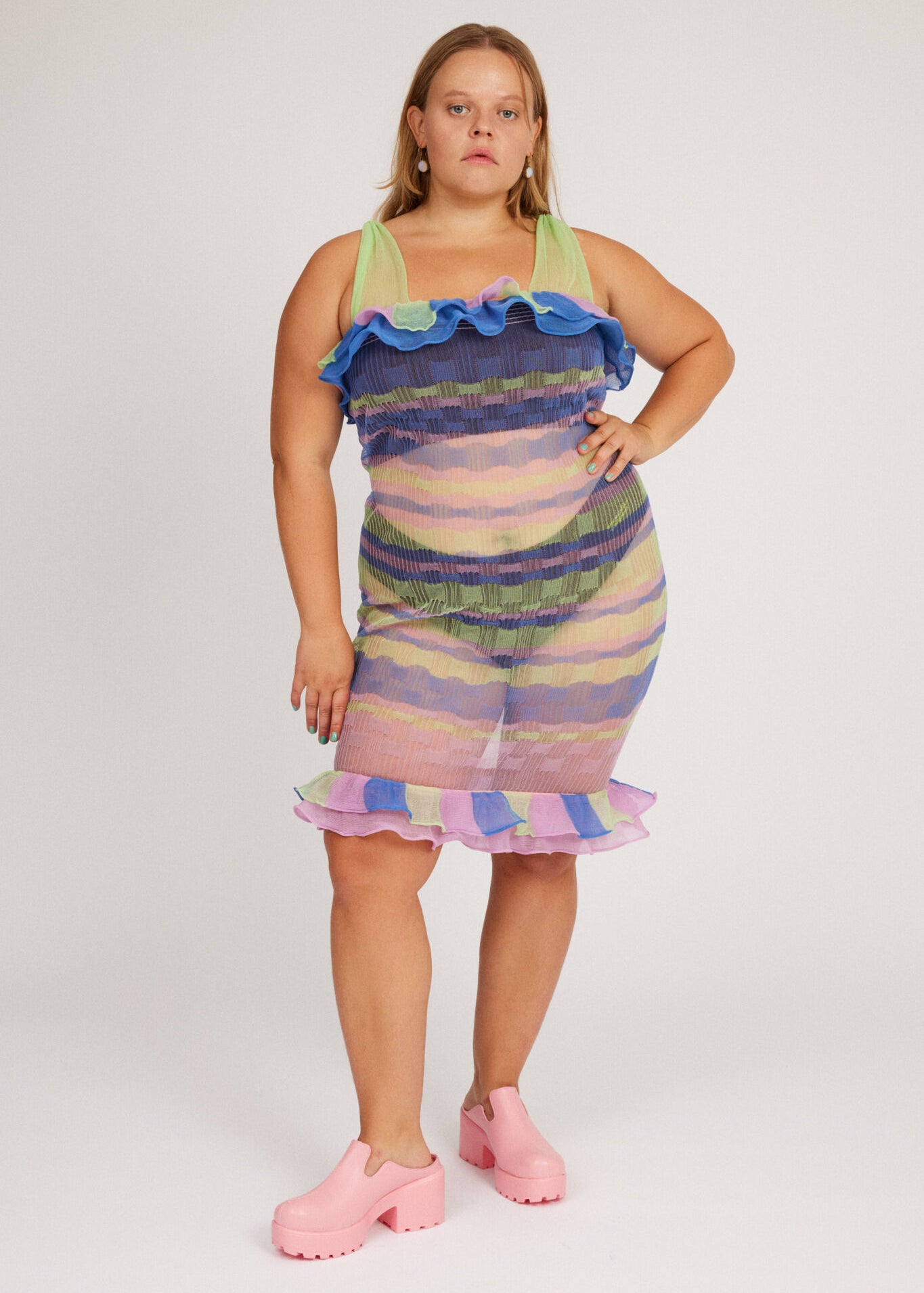 Loveable Dress in lilac and green is a transparent knitted strap dress in bold stripes with a ribbed bubble texture. The textile is lightweight, delicate and very flexible. The dress has a body fitted silhouette that adapts to the body. Detailed with frills.