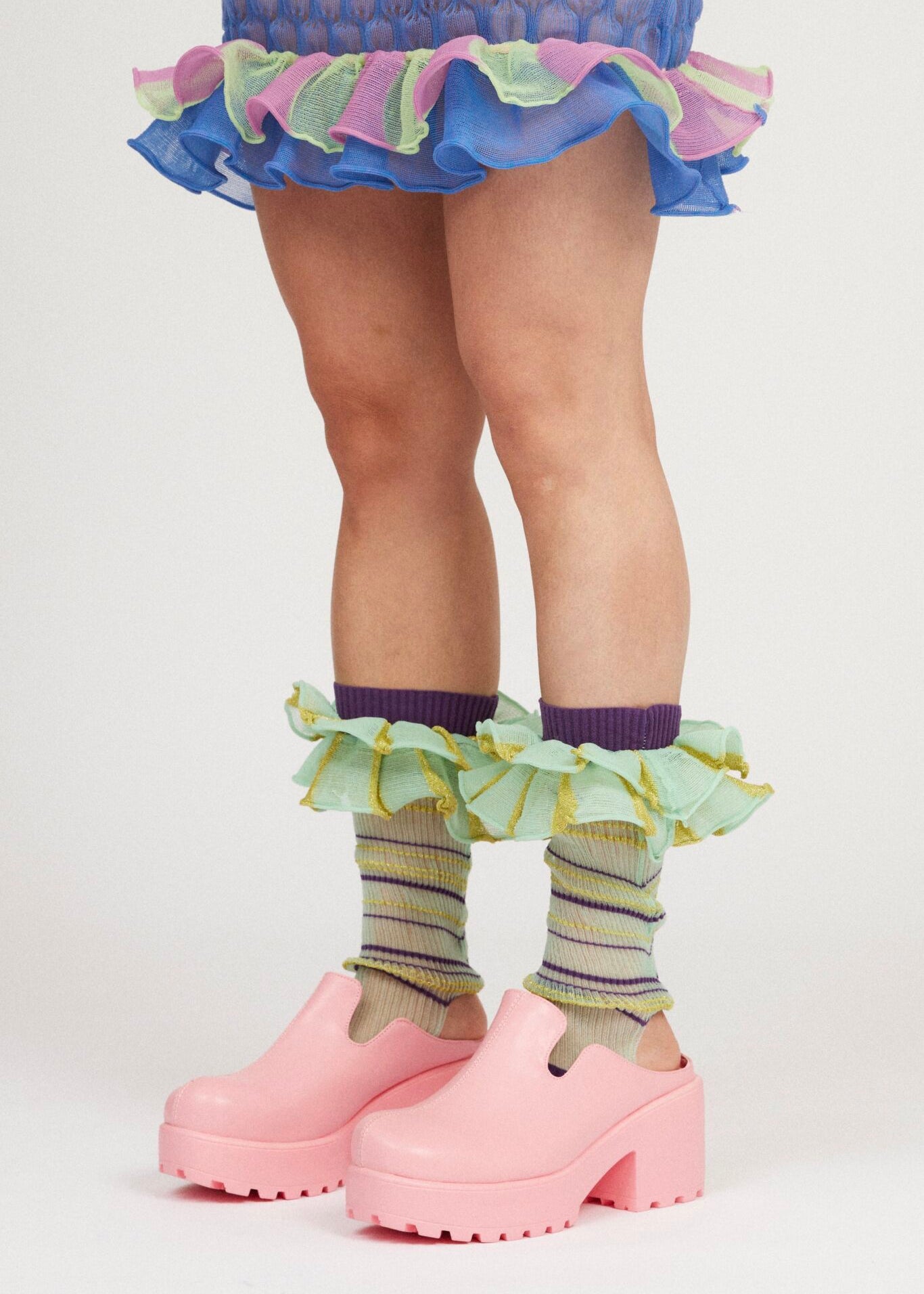 Mini Confetti Frills in mint green and purple are a knitted pair of transparent striped ruffle frills with a ribbed texture. The textile is lightweight, delicate and very flexible. Can be worn on both the arms and legs.