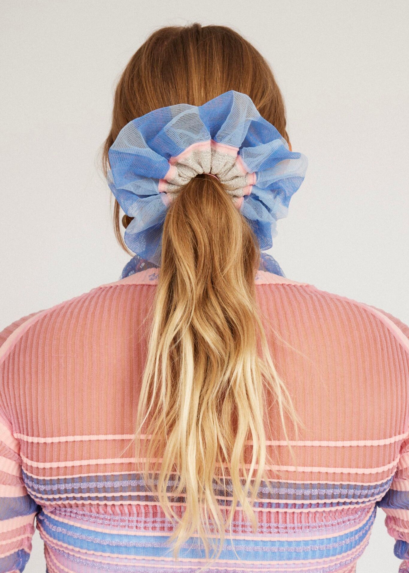Petunia Scrunchie in powder blue and pink is a knitted scrunchie in bold stripes. Made of transparent and shimmery yarns.