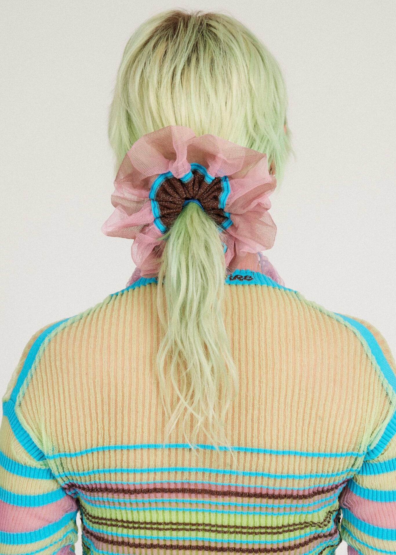 Petunia Scrunchie in tanned and pink is a knitted scrunchie in bold stripes. Made of transparent and shimmery yarns.