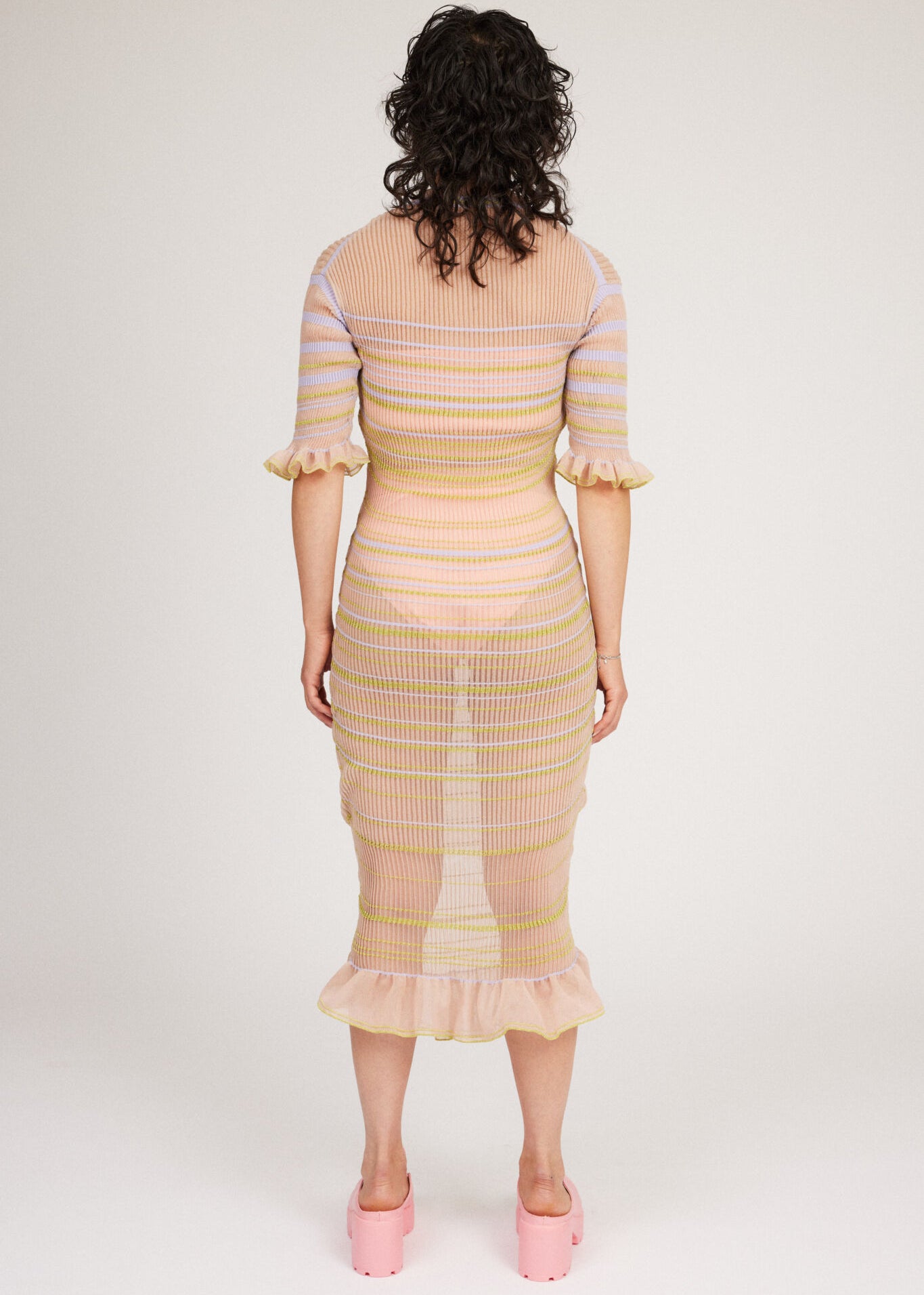 Sweet Secret Dress in peach blonde is a transparent knitted short sleeved high neck dress in gradient stripes with shimmery metallized yarn. The textile is lightweight, delicate and very flexible. The dress has a body fitted silhouette that adapts to the body. Detailed with frills and a logo in the back of neck.