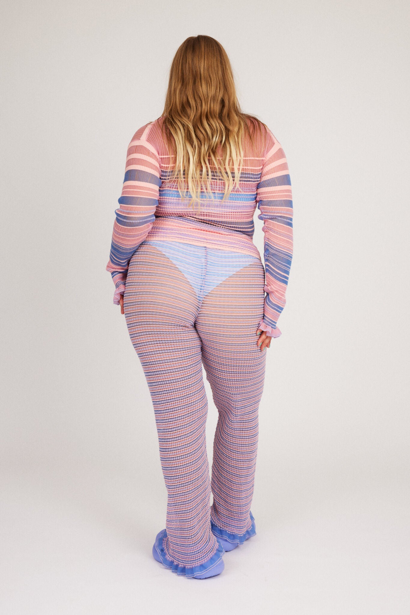 Sweet Secret Jumper in pink and powder blue is a knitted transparent high neck jumper in all over bold stripes detailed with shimmery metallized yarn. The textile is lightweight, delicate and very flexible. The jumper has a body fitted silhouette that adapts to the body. Detailed with frills and a logo in the back of the neck.