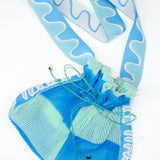Twisted Frill Bag in blue and mint green is a knitted transparent crossbody cinch bag in twisted chess stripes. Detailed with ruffles, a logo jacquard strap and an adjustable opening.