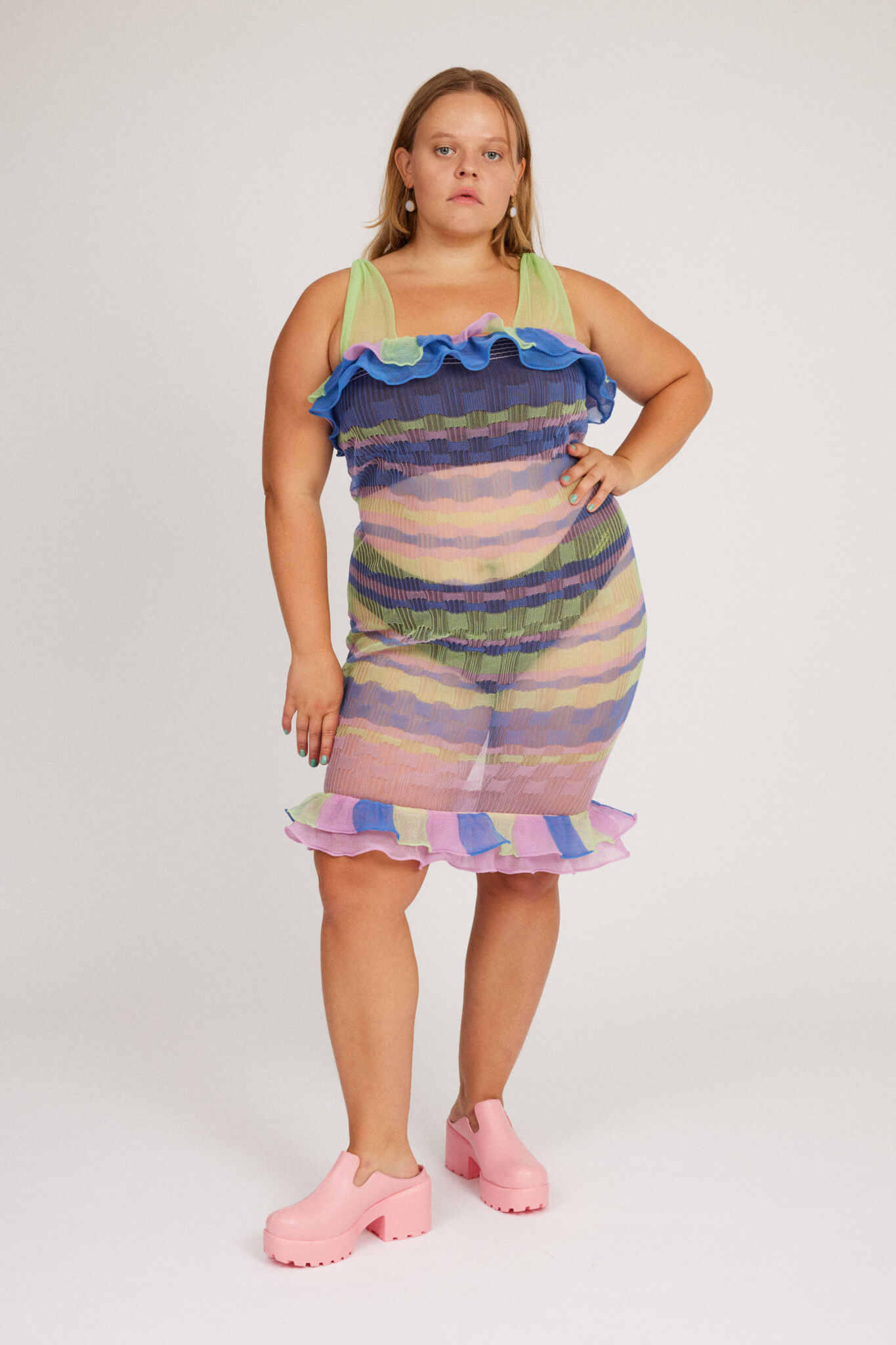 Loveable Dress in lilac and green is a transparent knitted strap dress in bold stripes with a ribbed bubble texture. The textile is lightweight, delicate and very flexible. The dress has a body fitted silhouette that adapts to the body. Detailed with frills.