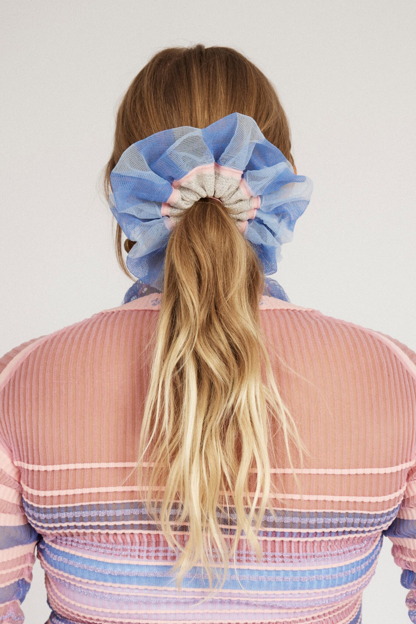 Petunia Scrunchie in powder blue and pink is a knitted scrunchie in bold stripes. Made of transparent and shimmery yarns.