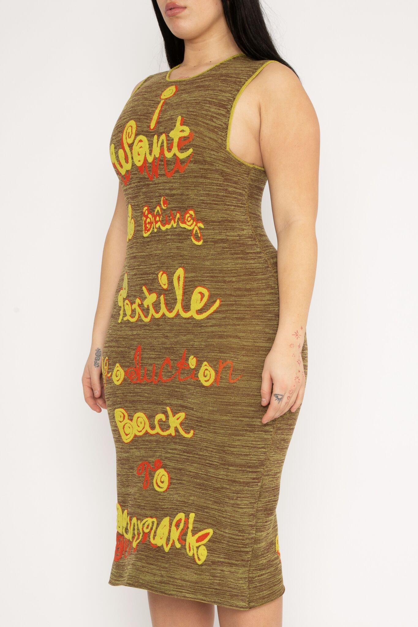 My Mission Dress in brown and yellow is a body fitted knitted jacquard dress in melange decorated with 3D statement artwork in bold colours. The dress is cut for a slim fit and has a slight shaping effect. A zipper has been added to make it easier to slide into. The merino wool makes the textile soft, and the nylon very flexible, meaning the dress adapts to the body wearing it. The My Mission Dress is a tribute to our core values and production methods, with the text in the front stating ”I want to bring textile production back to Denmark” and the back ”I simply don’t believe in mass production”. Available in 3 different colours and sizes.