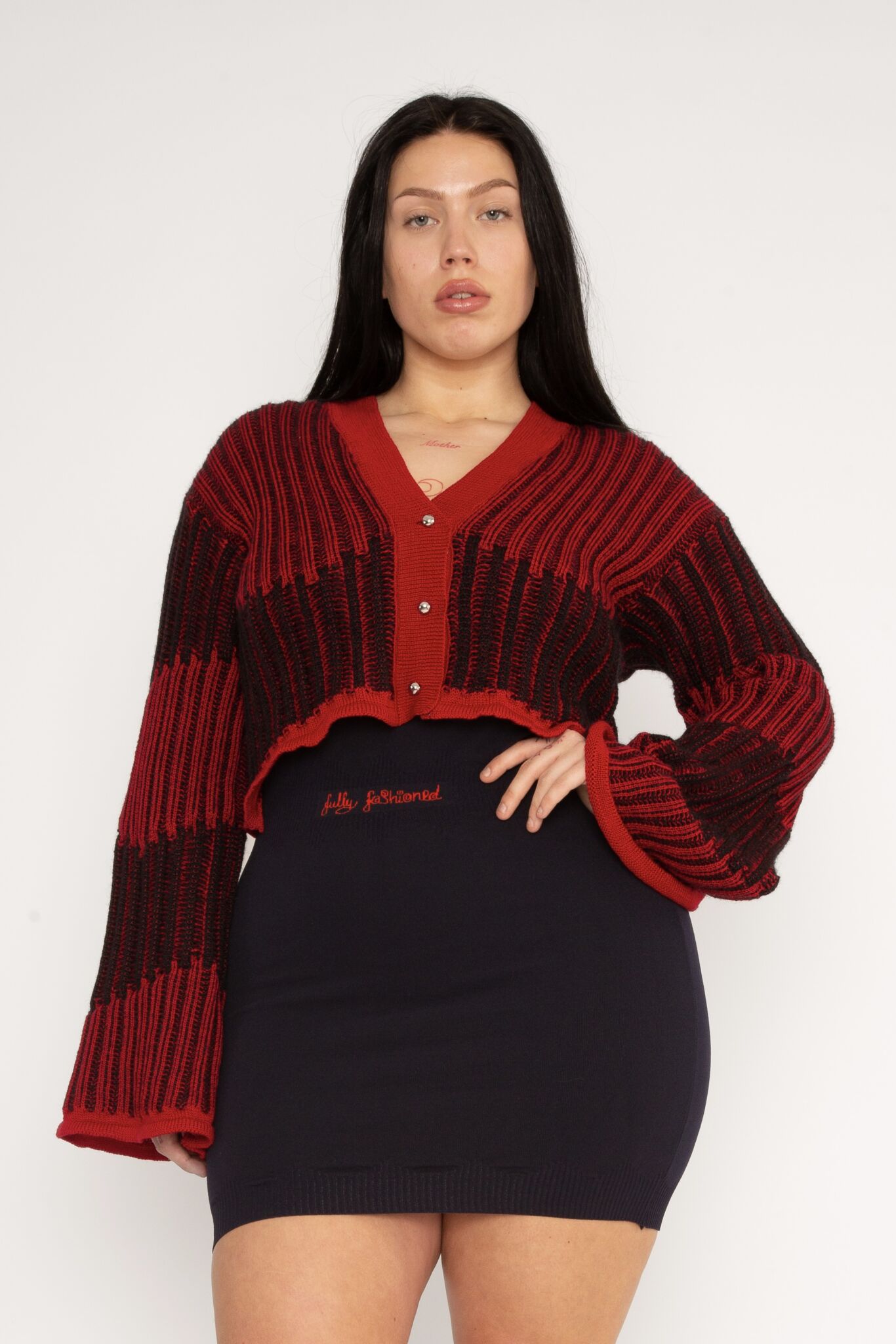 Wavy Wool Cardigan in red and black is a knitted cropped mohair cardigan with flared sleeves and all-over wavy stripes. Detailed with a heart in the back. The cardigan has a ribbed V-shaped neckline, a three-button closure and is cut for a slightly loose fit. The textile is fluffy, non-itchy and comfortable against the skin. The Wavy Wool Cardigan is also available in turquoise and comes in 3 different sizes.